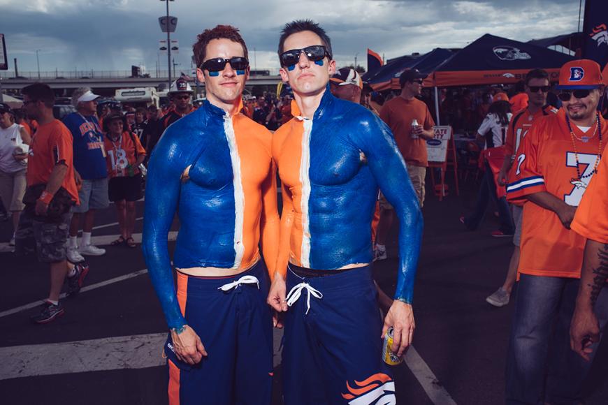 2 Broncos Superfans wearing blue and orange body paint and sunglasses.