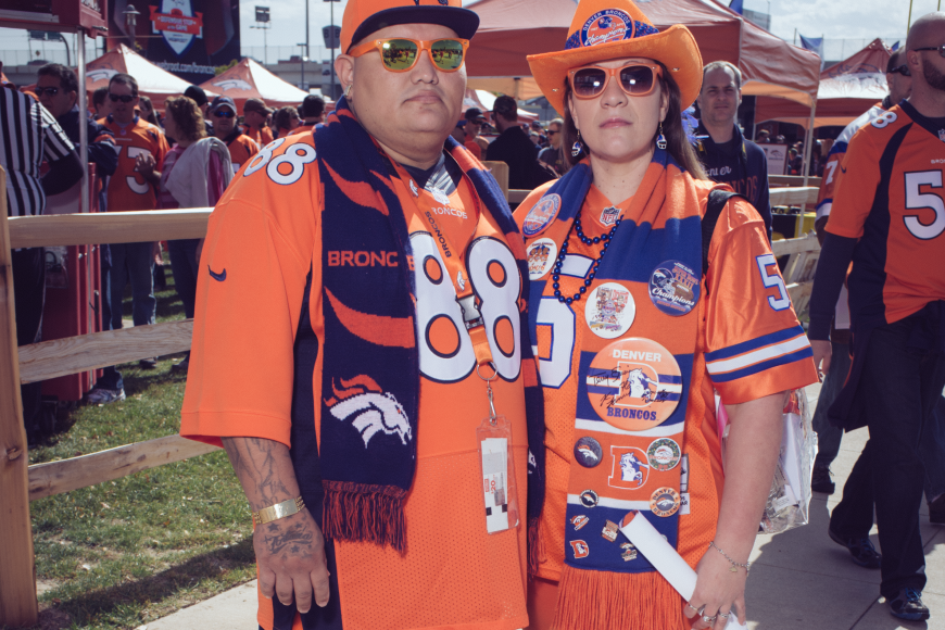 2 broncos superfans with bronco themed scarves and hats.