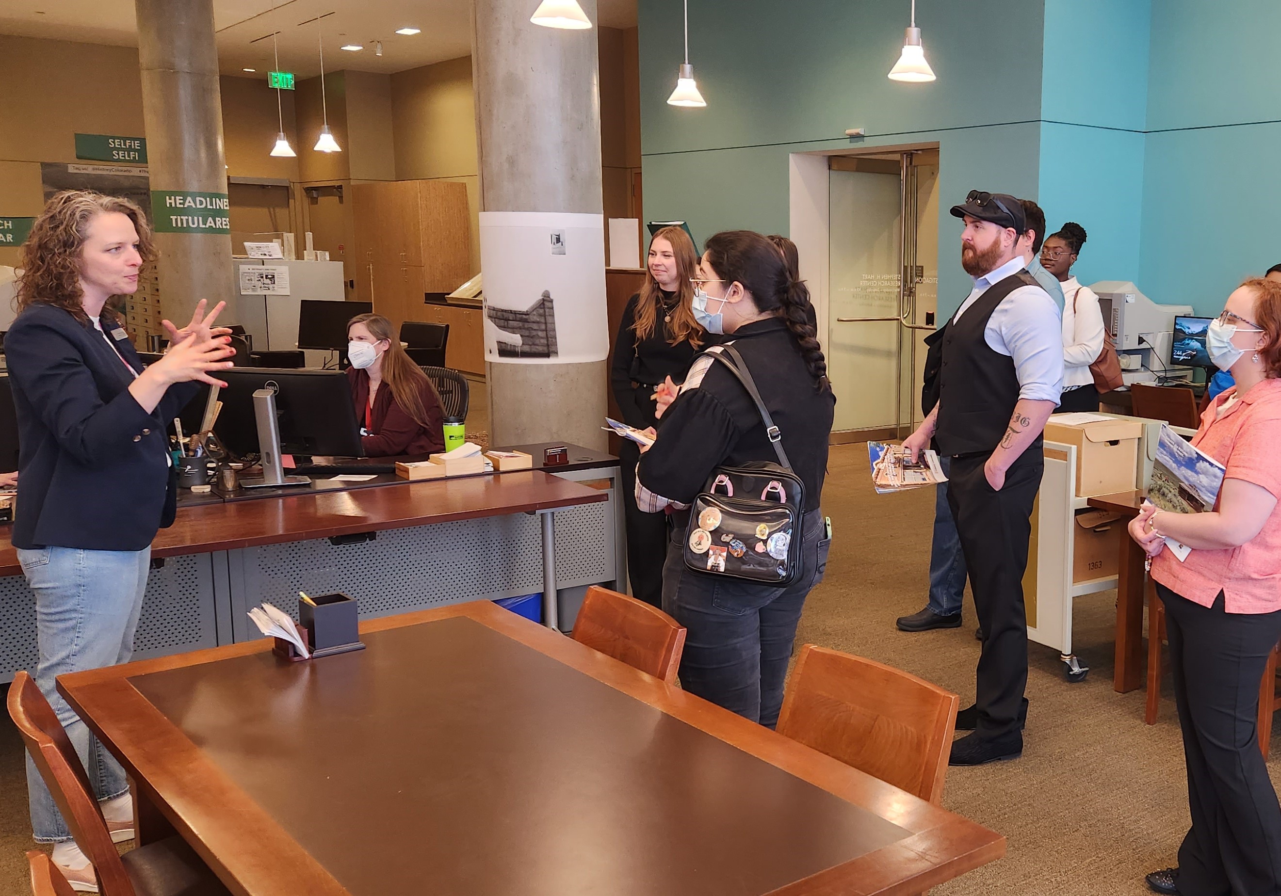Exhibits and Loan Registrar Kimberly Kronwall speaking to a group of visitors in the Stephen H. Hart research center by a large table.