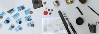 An artifact kit holding a collection of artifacts such as a mining tools as well as photos on a table. 