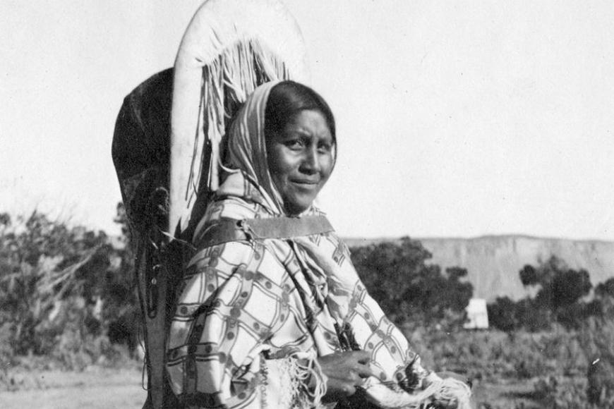 Ute woman carrying her baby in a traditional hide cradleboard, 1895-1905.