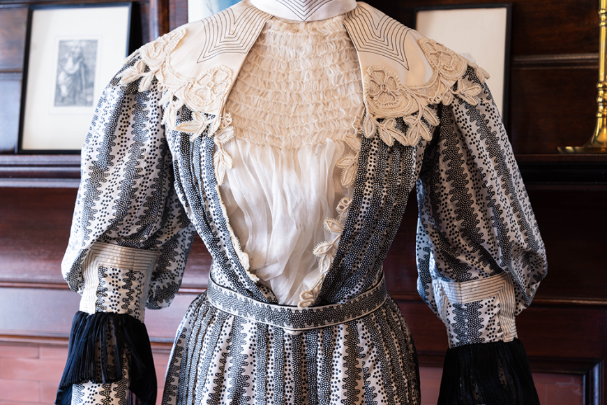 Close up of a mannequin dressed in a patterned, grey Victorian dress.