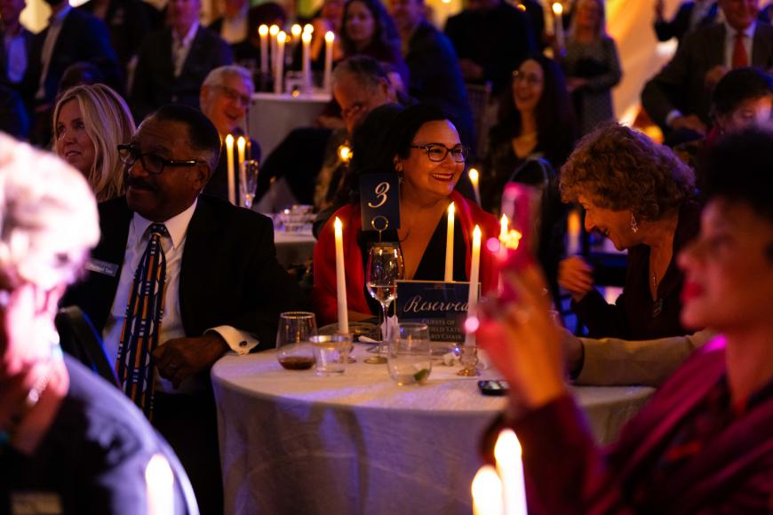 Colorado! Friends Circle members sit at candlelit tables and smile together in a large crowd.