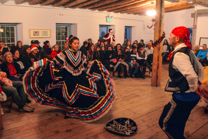 A crowd inside Fort Garland watches 2 traditional folklorico dancers.