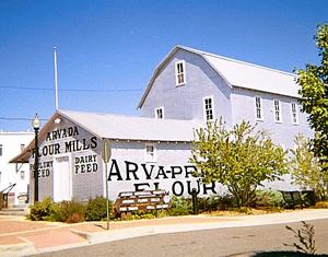 A view of the mill with Dutch Gabled roof, and large lettering on the front portion of the building. 